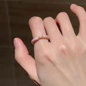 Close-up detail shot of the minimalist pink enamel stackable ring worn on a finger elegantly.