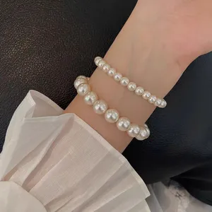 Vista detallada de pulseras de perlas de doble capa en la muñeca con diseño elegante.