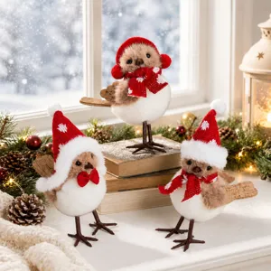 Close-up of cute Christmas plush bird ornaments with red hats and cozy scarves on a snowy shelf.