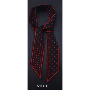 Primo piano di un elegante foulard twilly nero con pois rossi e un bordo rosso brillante.