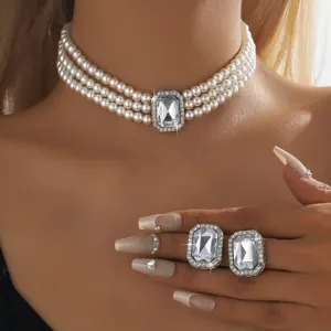 Primo piano che mostra l'elegante girocollo di perle multistrato e gli anelli di cristallo abbinati.