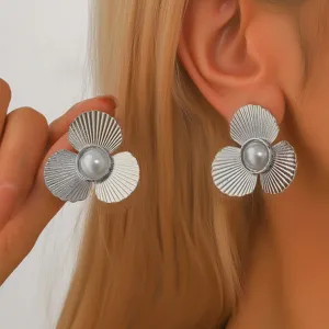 Primo piano dettagliato di orecchini a fiore in metallo argentato retrò con perla.