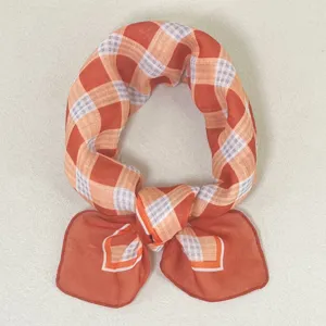 Gedetailleerd uitzicht op een chique oranje geruite sjaal, lichtgewicht stof met strik.