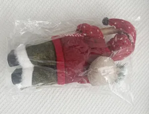 Vue détaillée de la poupée du Père Noël dans l'emballage avec texture tricotée et sac à dos.