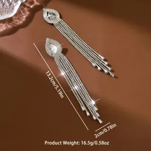 Dettaglio di lunghi orecchini con nappe in strass scintillanti e pietra a goccia, eleganti.