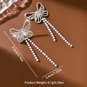 Dettaglio di orecchini con fiocco in strass scintillante ed eleganti nappe di perle lucenti.