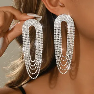 Primo piano di orecchini pendenti in strass a forma di U a cascata indossati, molto eleganti.