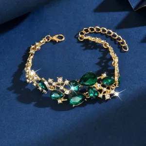 Primo piano di bracciale in lega dorata con cristalli verde smeraldo e strass luminosi.
