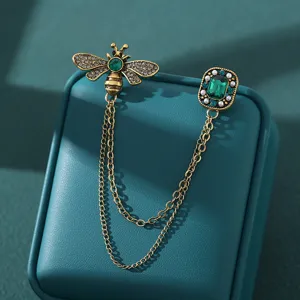Vintage bee and emerald crystal chain brooch, elegant dual pin fashion jewelry for women.