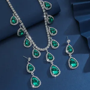 Primo piano di un set di collana e orecchini con strass a goccia verde e catena brillante.