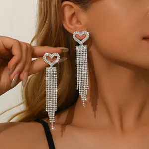 Primo piano di orecchini lunghi con frange di strass a cuore, dettaglio di gioielli eleganti.