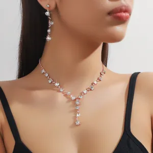 Dettaglio in primo piano di collana con strass scintillanti e orecchini oro rosa.