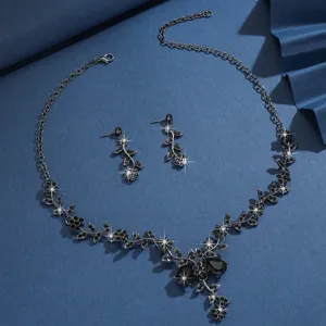 Primo piano dettagliato di un set collana e orecchini con vite di fiori in strass neri.