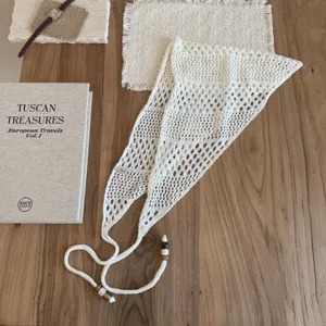 Gros plan détail du foulard triangle en tricot ajouré crème avec perles en bois.
