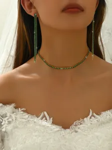 Close-up shot of a glamorous green rhinestone choker necklace and long earrings set on model.
