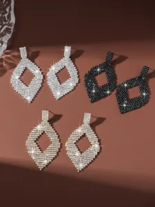 Vista dettagliata di eleganti orecchini pendenti con strass a rombo, gioielli geometrici scintillanti.