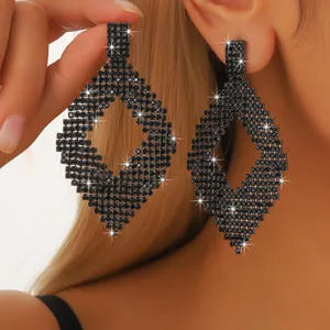 Primo piano di orecchini lunghi geometrici in strass nero per feste eleganti donne