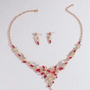 Detalles de conjunto de collar y pendientes dorados con pedreria roja y transparente.