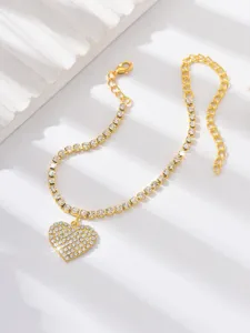 Dettaglio cavigliera cuore con strass, catena dorata pavé di cristalli scintillanti.