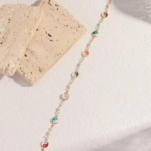 Goldfarbene Kettendarmband mit bunten Emaille Yin-Yang Anhängern und Perlendetails.
