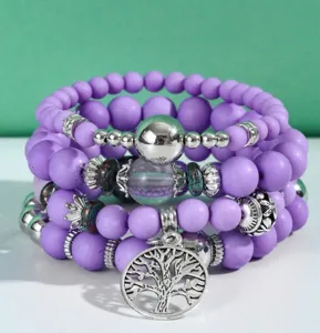 Vista dettagliata del set bracciali boho multistrato con perline viola e ciondolo albero della vita.