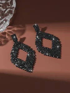 Orecchini lunghi geometrici in strass nero esagerati dettaglio primo piano scintillante.
