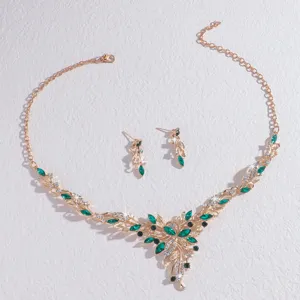 Vista detallada del collar y aretes de joyería con diamantes de imitación de cristal verde.