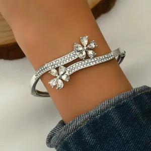 Detailed close-up of a stunning silver-tone crystal flower bypass bangle bracelet worn on wrist.