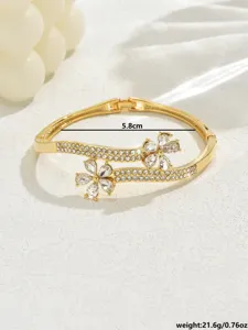 Close-up of gold tone rhinestone floral bangle bracelet featuring dual flower details.
