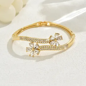 Gold tone rhinestone flower bangle bracelet detail view showcasing sparkling crystal stones.