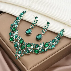 Gros plan sur l'ensemble de bijoux en strass et cristaux verts, détails de collier et boucles.