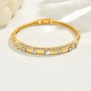 Dettaglio di bracciale geometrico dorato con strass scintillanti e finitura lucida.