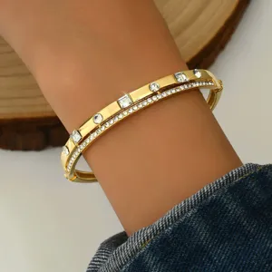 Bracciale rigido dorato con strass a doppio strato, elegante gioiello geometrico in cristallo.