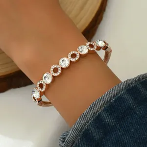 Primo piano dettaglio di un bracciale geometrico alla moda in oro rosa con strass al polso.