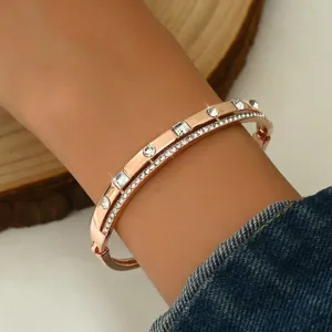 Primo piano bracciale rigido doppio oro rosa, dettaglio di eleganti strass geometrici raffinati.