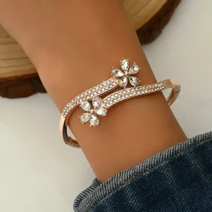Rose gold cuff bracelet featuring sparkling rhinestone floral accents and stylish crossover design.