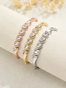 Primo piano di tre bracciali rigidi in cristallo ondulato in oro rosa, oro e argento.