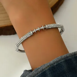 Primo piano dettagliato di un bracciale rigido geometrico in strass argentato al polso.