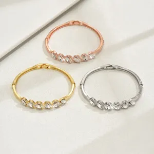 Elegante bracciale rigido geometrico in metallo con strass disponibile in oro rosa e argento.