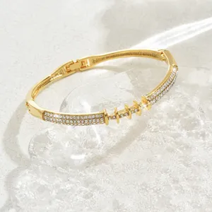 Foto di dettaglio del bracciale rigido geometrico dorato con pavé di strass scintillanti e intagli.