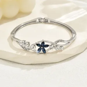 Detailed shot of a silver-tone floral bangle bracelet featuring a dark blue crystal flower.