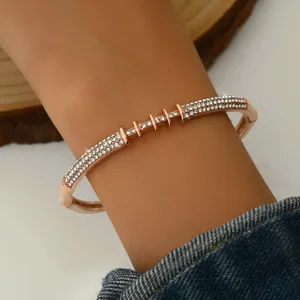 Bracciale rigido geometrico in strass oro rosa da donna, gioiello elegante e luminoso.