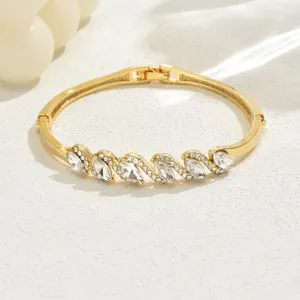 Elegante bracciale rigido geometrico in cristallo dorato con splendidi dettagli di strass.