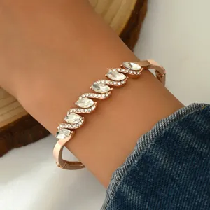 Bracciale rigido oro rosa con cristalli taglio marquise a onda, dettaglio di gioiello elegante donna.