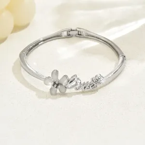 Detail shot of silver-toned flower bangle bracelet with "Love" script design for daily wear.
