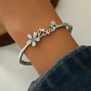 Silver-tone metal hinged bangle bracelet featuring a white cat eye stone flower and Love script.