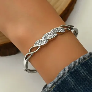 Primo piano di un bracciale geometrico argentato con strass pavé indossato al polso.