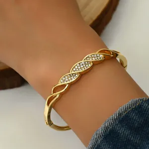 Bracciale rigido intrecciato in strass d'oro dettaglio primo piano con design pavé di cristalli.