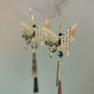 Chinese style long tassel earrings detail view, vintage butterfly pendant with ink calligraphy.