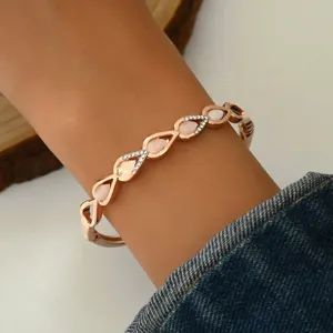 Primo piano del bracciale geometrico a goccia in oro rosa con strass e pietre rosa.